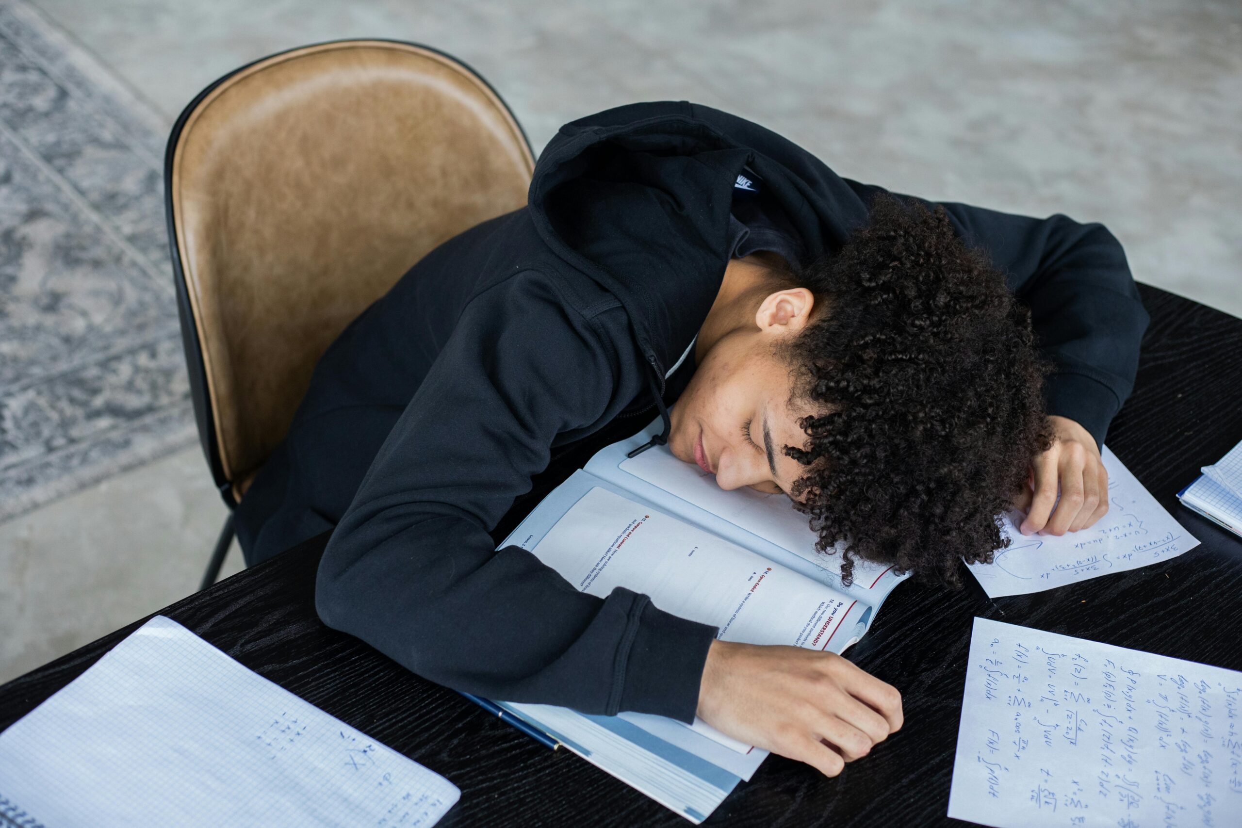 Male student laying his head on a notebook, asleep.